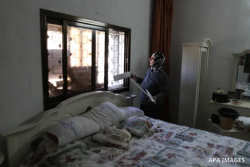 A Palestinian woman inspects a broken window of her house by Israeli settlers near the village of Burin, south of the West Bank city of Nablus, on Nov. 19, 2014. Photo by Nedal Eshtayah