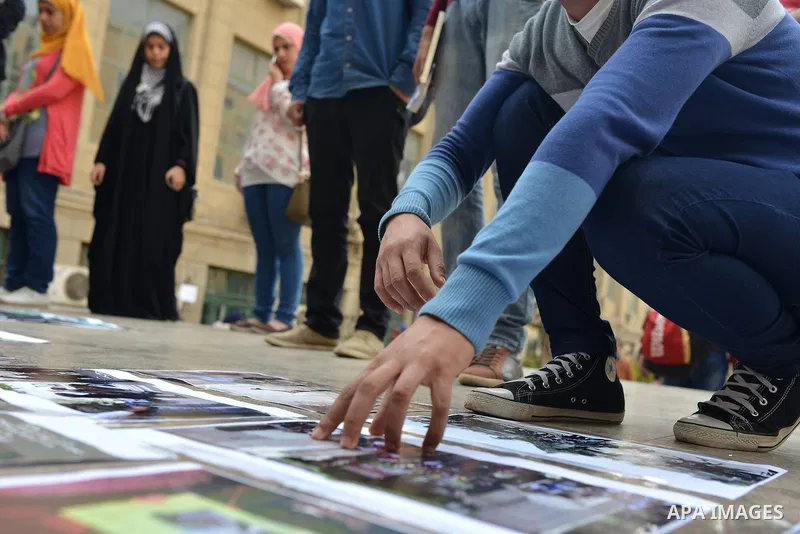 An Egyptian student glues photos on the ground during a street photo gallery organised by Misr Al-Qawia Party to commemorate the 3rd anniversary of deadly Mohamed Mahmoud clashes, at Cairo University on November 19, 2014...