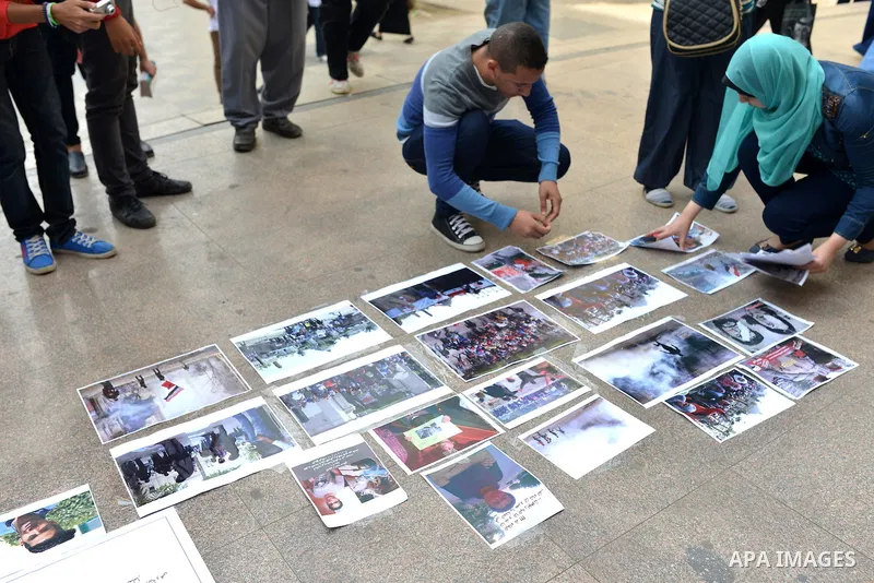 Egyptian students glue photos on the ground during a street photo gallery organised by Misr Al-Qawia Party to commemorate the 3rd anniversary of deadly Mohamed Mahmoud clashes, at Cairo University on November 19, 2014. A...