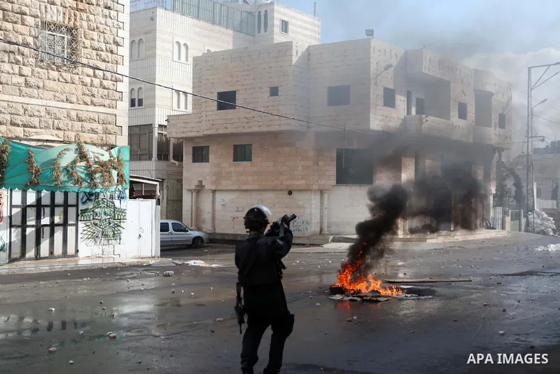 A member of Israeli security forces fires tear gas towards Palestinian protesters during clashes following a protest against the recent Israeli measures in Jerusalem, in the West Bank city of Hebron, November 21, 2014. I...