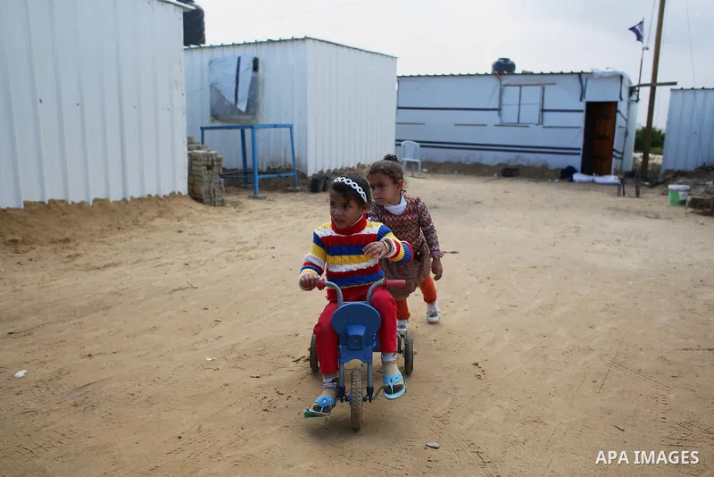 Palestinian children who live in a containers as a temporary replacement for their house that witnesses said was destroyed by Israeli shelling during the most recent conflict between Israel and Hamas play past their a te...