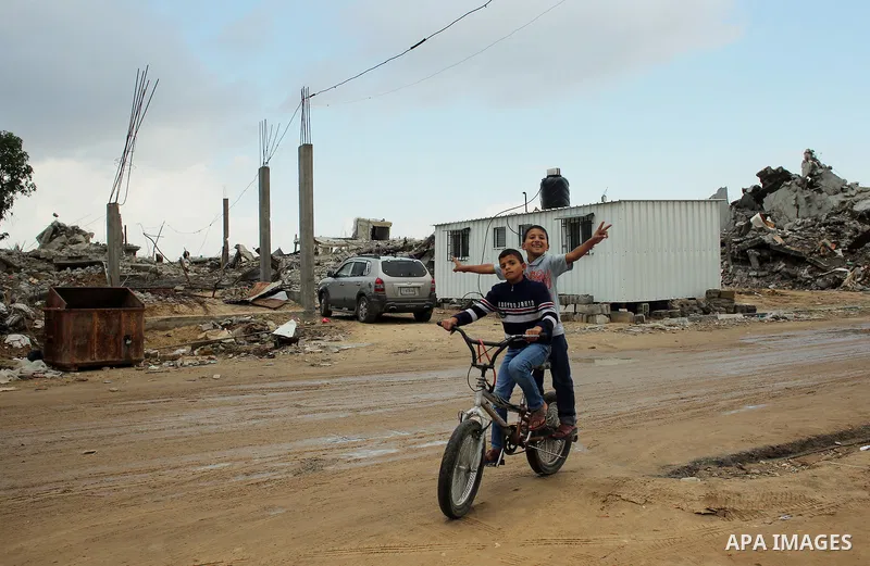 A Palestinian boy ride a bicycle on a rainy day past the temporary homes of Palestinian that witnesses said was destroyed by Israeli shelling during the most recent conflict between Israel and Hamas in Khan Younis in the...
