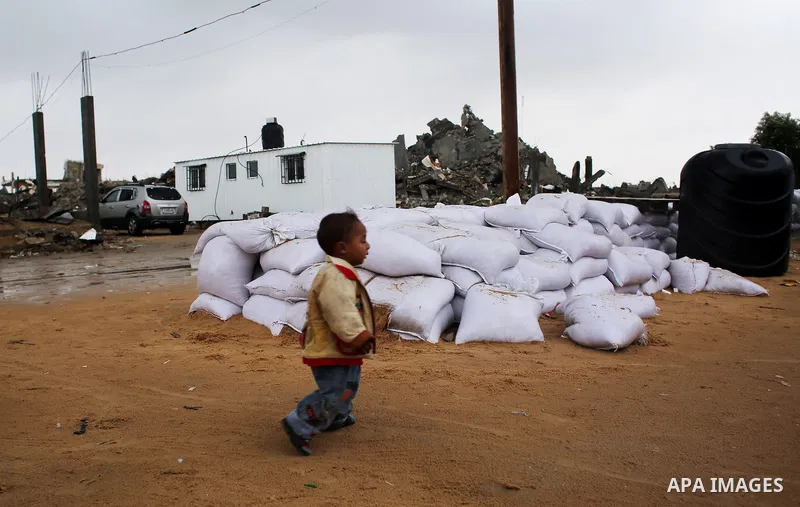 A Palestinian boy who lives in a containers as a temporary replacement for his house that witnesses said was destroyed by Israeli shelling during the most recent conflict between Israel and Hamas plays past his a tempora...
