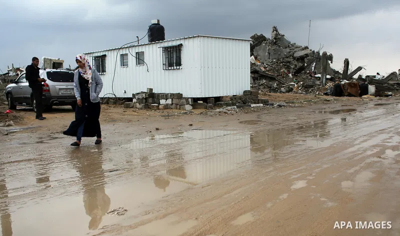 A Palestinian school girl walks on a rainy day past the temporary homes of Palestinian that witnesses said was destroyed by Israeli shelling during the most recent conflict between Israel and Hamas in Khan Younis in the...