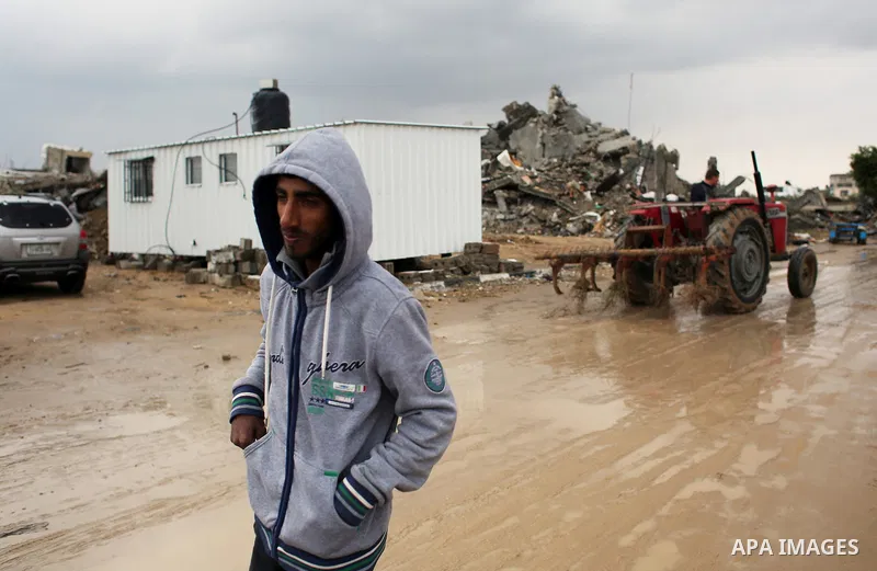 A Palestinian man walks on a rainy day past the temporary homes of Palestinian that witnesses said was destroyed by Israeli shelling during the most recent conflict between Israel and Hamas in Khan Younis in the southern...