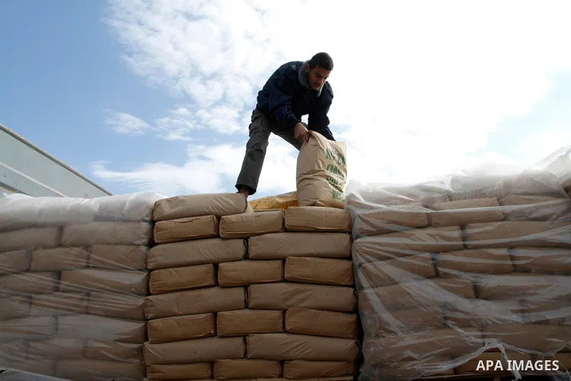 A Palestinian worker adjusts bags of cement loaded on a truck that entered the Gaza Strip from Israel through the Kerem Shalom crossing in Rafah in the southern Gaza Strip on November 25, 2014. Twenty-eight trucks of cem...