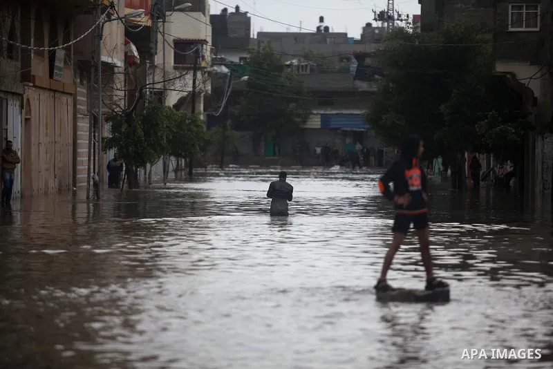 Palestinians make their way through a flooded street during heavy rains in Gaza City on November 27, 2014 as a fierce winter storm which has been battering the region for the past four days. Photo by Ashraf Amra