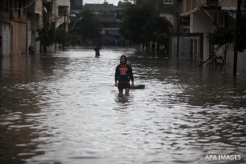 Palestinians make their way through a flooded street during heavy rains in Gaza City on November 27, 2014 as a fierce winter storm which has been battering the region for the past four days. Photo by Ashraf Amra