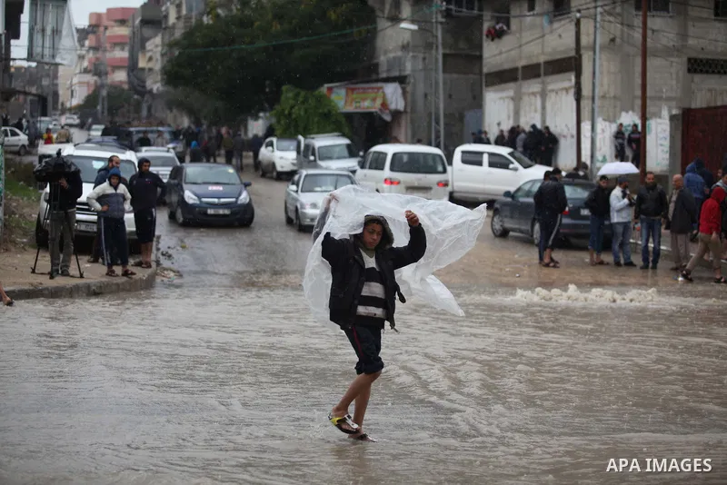 A Palestinian boy makes his way through a flooded street during heavy rains in Gaza City on November 27, 2014 as a fierce winter storm which has been battering the region for the past four days. Photo by Ashraf Amra
