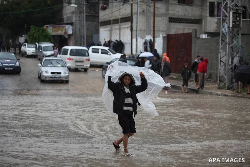 A Palestinian boy makes his way through a flooded street during heavy rains in Gaza City on November 27, 2014 as a fierce winter storm which has been battering the region for the past four days. Photo by Ashraf Amra
