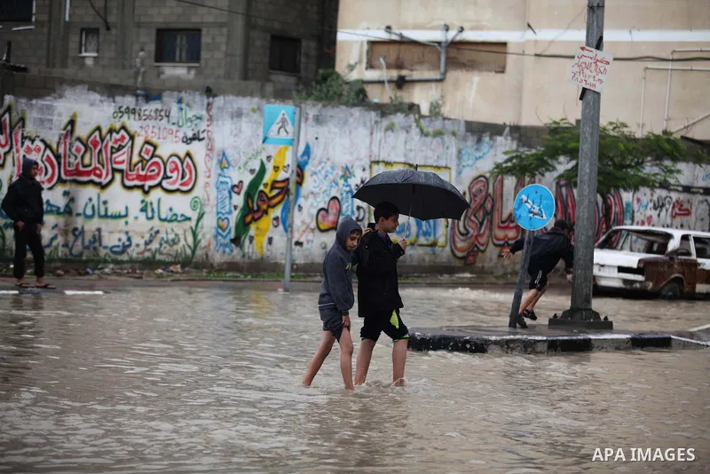 Palestinians make their way through a flooded street during heavy rains in Gaza City on November 27, 2014 as a fierce winter storm which has been battering the region for the past four days. Photo by Ashraf Amra