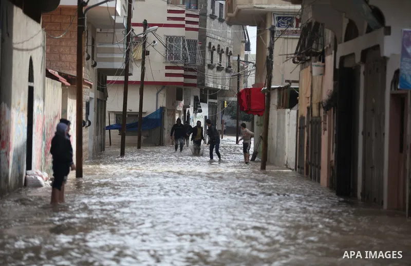 Palestinians make their way through a flooded street during heavy rains in Gaza City on November 27, 2014 as a fierce winter storm which has been battering the region for the past four days. Photo by Ashraf Amra
