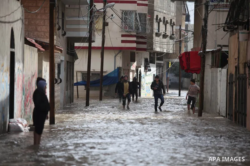 Palestinians make their way through a flooded street during heavy rains in Gaza City on November 27, 2014 as a fierce winter storm which has been battering the region for the past four days. Photo by Ashraf Amra