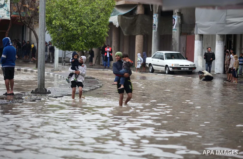 Palestinians make their way through a flooded street during heavy rains in Gaza City on November 27, 2014 as a fierce winter storm which has been battering the region for the past four days. Photo by Ashraf Amra