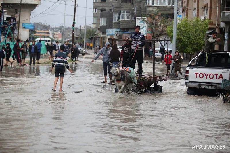 Palestinians ride a donkey cart as they make their way through a flooded street during heavy rains in Gaza City on November 27, 2014 as a fierce winter storm which has been battering the region for the past four days. Ph...
