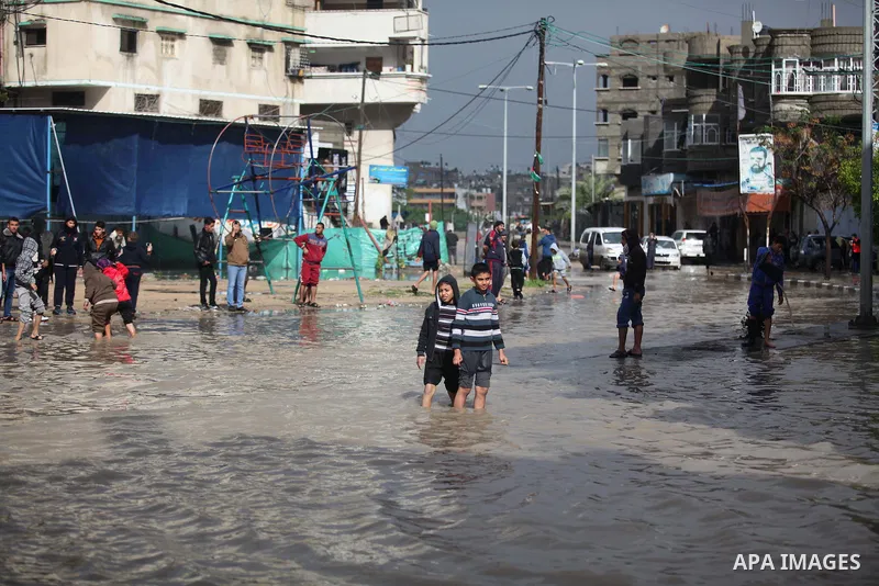 Palestinians make their way through a flooded street during heavy rains in Gaza City on November 27, 2014 as a fierce winter storm which has been battering the region for the past four days. Photo by Ashraf Amra