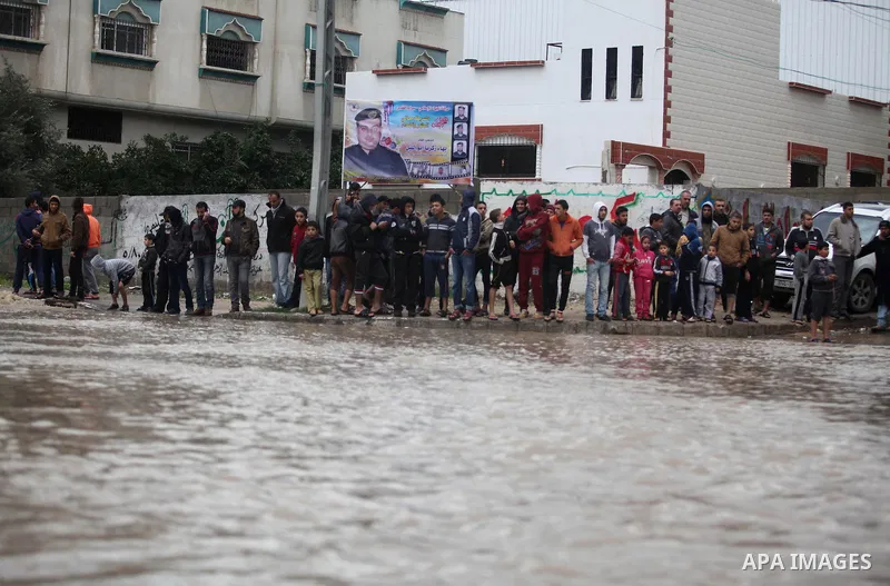 Palestinians stand in front of a flooded road following heavy rain in Gaza City November 27, 2014. The civil defence asked residents in an area east of Gaza City to evacuate their homes to avoid being trapped in flood wa...