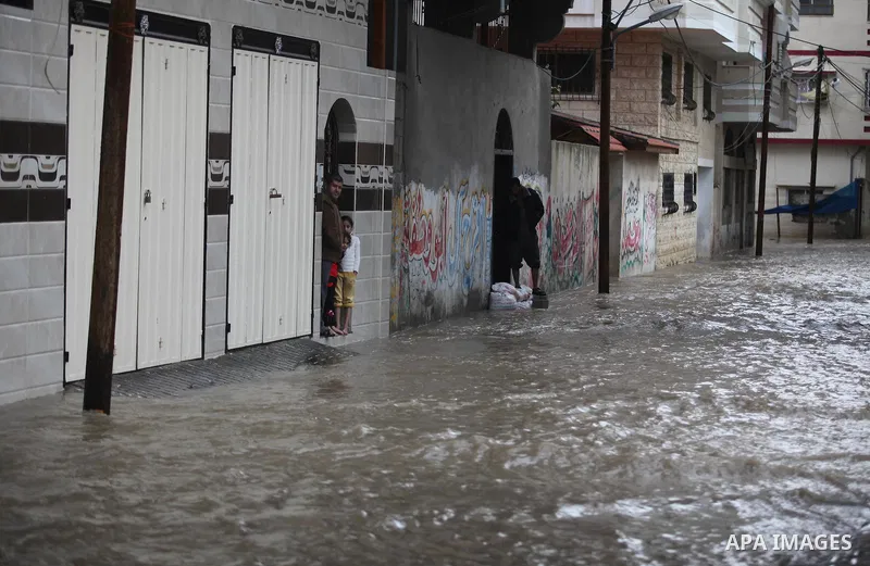 Palestinians stand in front of their family house during heavy rain in Gaza City, on November 27, 2014 as a fierce winter storm which has been battering the region for the past four days. Photo by Ashraf Amra
