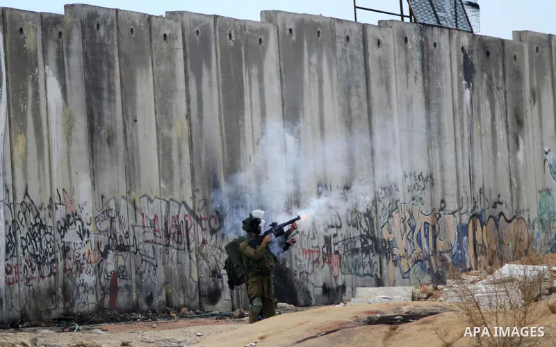 A member of Israeli security forces fires tear gas towards Palestinian protesters following a protest against Israeli restrictions to Al-Aqsa Mosque in Jerusalem, at the Qalandia checkpoint near the West Bank city of Ram...