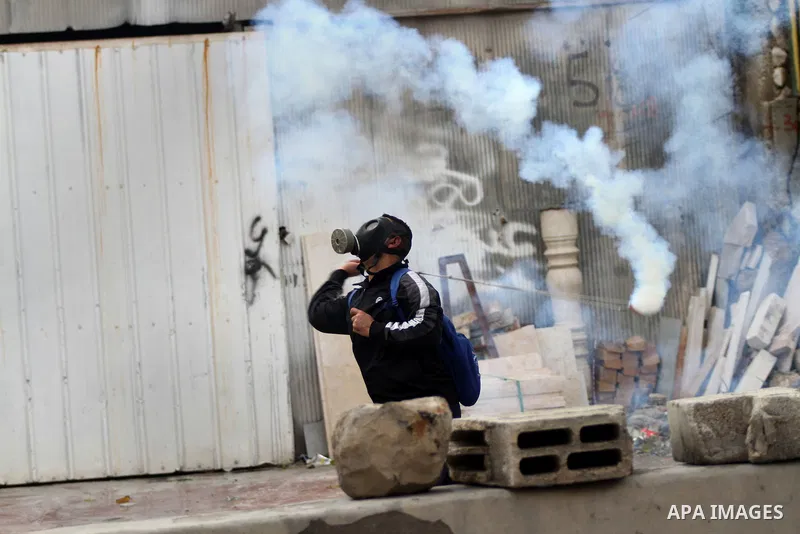 A Palestinian protester throws back a tear gas canister fired by Israeli security forces during clashes following a protest against Israeli restrictions to Al-Aqsa Mosque in Jerusalem, at the Qalandia checkpoint near the...