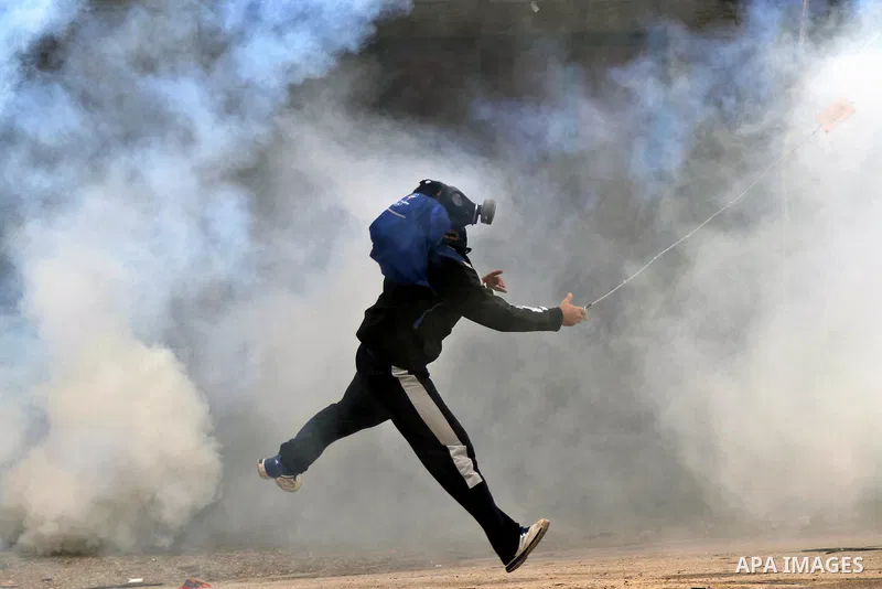 A Palestinian protester uses a slingshot to throw a stone towards Israeli security forces during clashes following a protest against Israeli restrictions to Al-Aqsa Mosque in Jerusalem, at the Qalandia checkpoint near th...