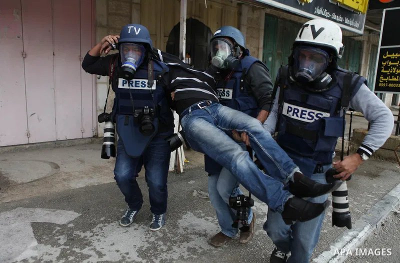 Palestinian photographers carry a wounded protester during clashes with Israeli security forces following a protest against Israeli restrictions to Al-Aqsa Mosque in Jerusalem, at the Qalandia checkpoint near the West Ba...