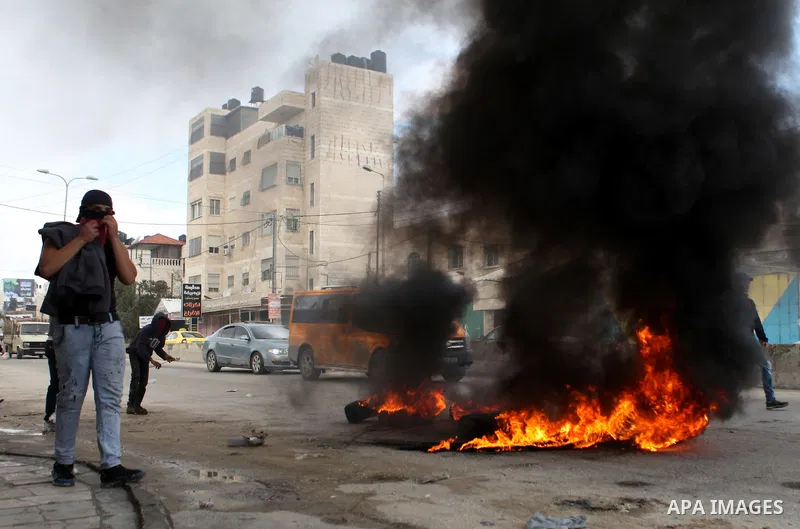 Palestinian protesters burn tires during clashes with Israeli security forces following a protest against Israeli restrictions to Al-Aqsa Mosque in Jerusalem, at the Qalandia checkpoint near the West Bank city of Ramalla...