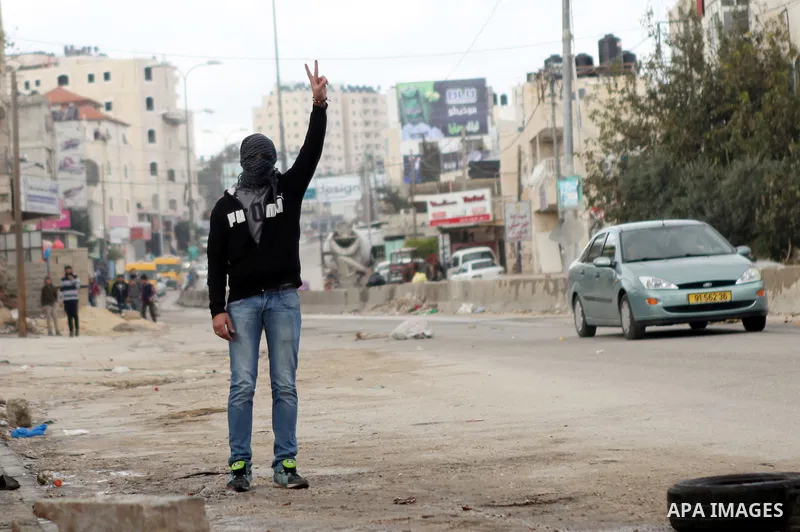 A Palestinian protester flashes a victory sign during clashes with Israeli security forces following a protest against Israeli restrictions to Al-Aqsa Mosque in Jerusalem, at the Qalandia checkpoint near the West Bank ci...