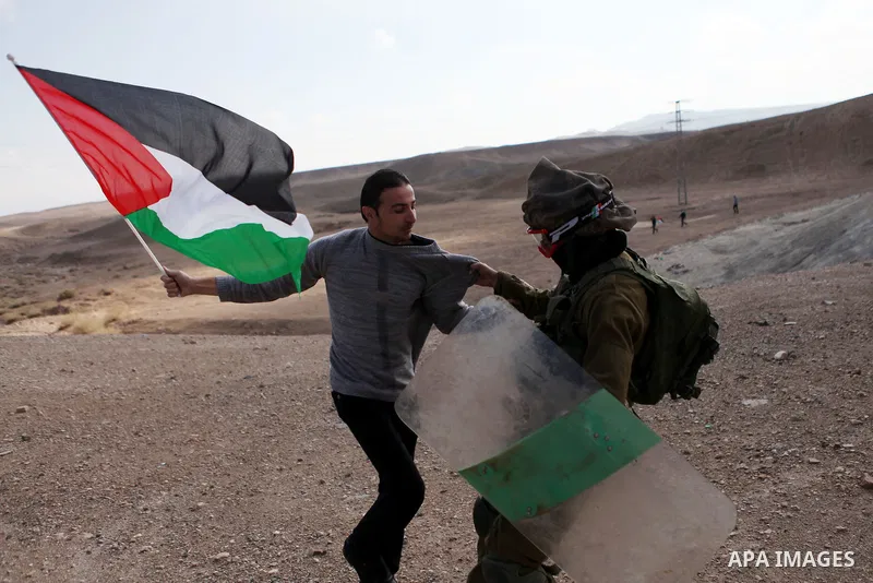 A Palestinian protester holding a Palestinian flag scuffles with Israeli soldiers during clashes following a protest against Jewish settlements, near the West Bank city of Jericho November 28, 2014. Photo by Shadi Hatem