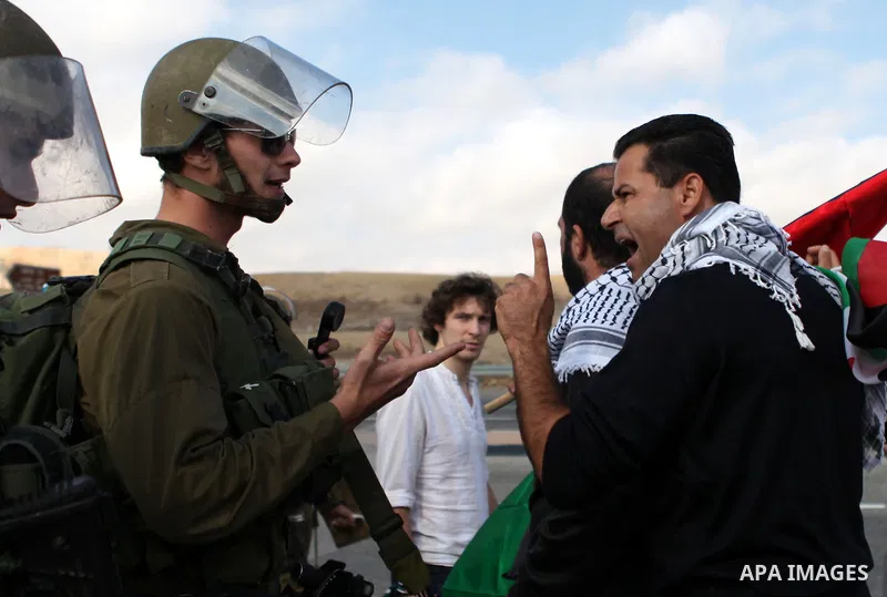 A Palestinian protester argues with an Israeli soldier as they try to block a highway between Jerusalem and the Dead Sea near the West Bank town of Jericho Friday, Nov. 28, 2014. Photo by Shadi Hatem