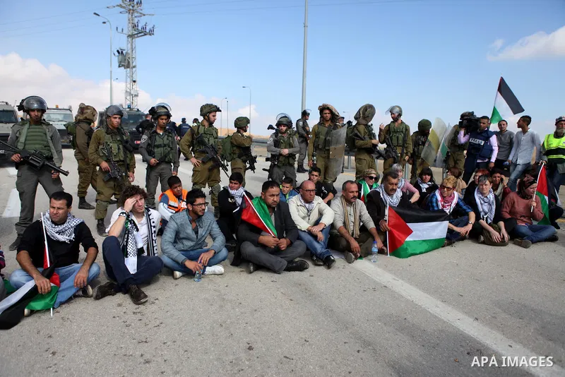 Palestinian protesters pray as Israeli soldiers and border policemen stand guard as they try to block a highway between Jerusalem and the Dead Sea near the West Bank town of Jericho Friday, Nov. 28, 2014. Photo by Shadi...