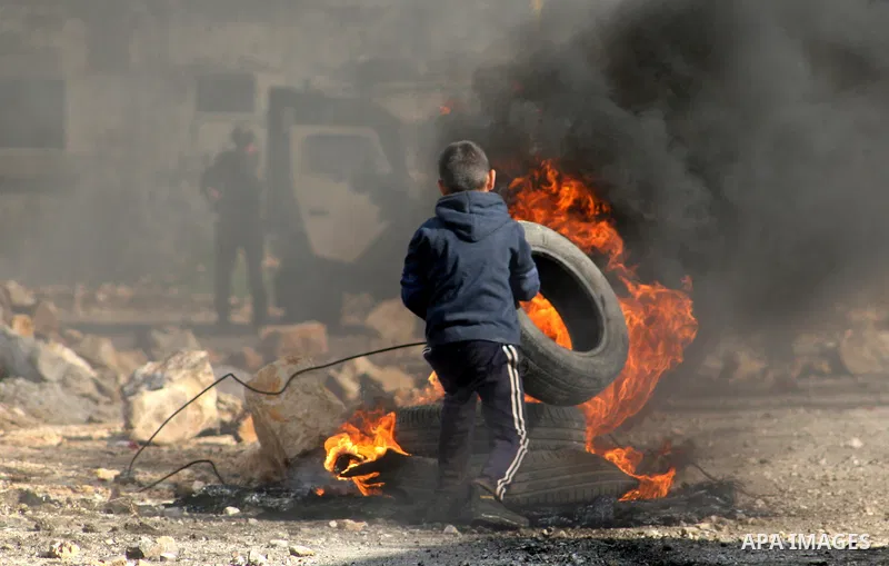 A Palestinian boy burns tires during clashes with Israeli security forces in a protest against the expropriation of Palestinian land by Israel following Friday prayers in the village of Kafr Qaddum, near Nablus, November...