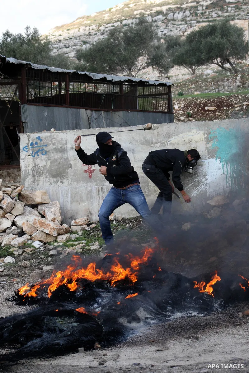 A Palestinian protester uses a slingshot to throw stones at Israeli security forces during clashes in a protest against the expropriation of Palestinian land by Israel following Friday prayers in the village of Kafr Qadd...