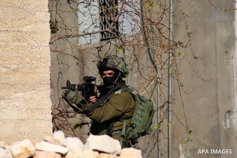 A member of Israeli security forces aims his gun at Palestinian protesters during clashes in a protest against the expropriation of Palestinian land by Israel following Friday prayers in the village of Kafr Qaddum, near...
