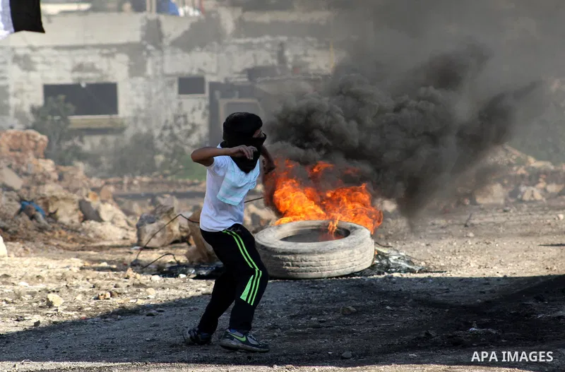 A Palestinian boy uses a slingshot to throw stones at Israeli security forces during clashes in a protest against the expropriation of Palestinian land by Israel following Friday prayers in the village of Kafr Qaddum, ne...