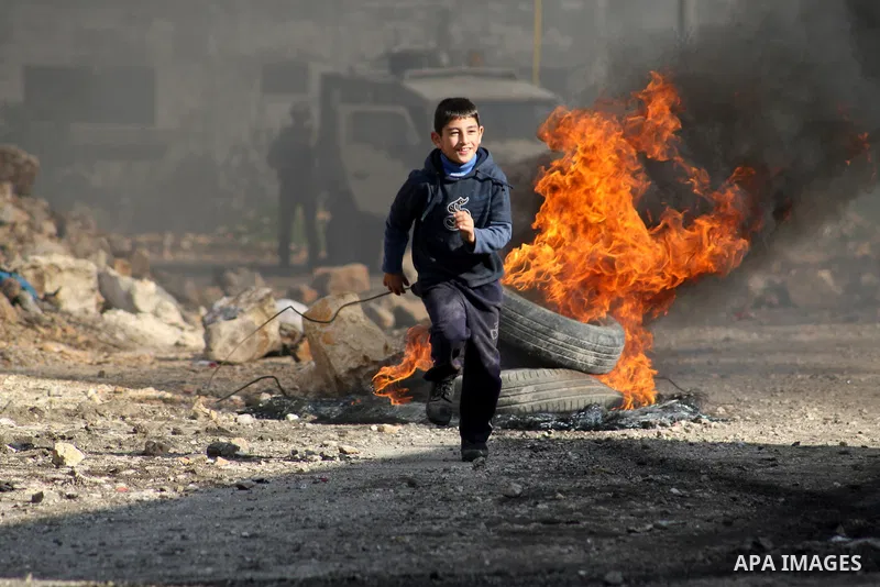 A Palestinian boy runs back after during clashes with Israeli security forces in a protest against the expropriation of Palestinian land by Israel following Friday prayers in the village of Kafr Qaddum, near Nablus, Nove...