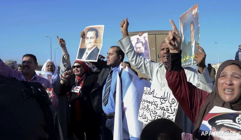 Supporters of former Egyptian President Hosni Mubarak chant slogans as they wait for him to be transferred to a court, in front of the court, in Cairo November 29, 2014. An Egyptian court is due to deliver its verdict on...