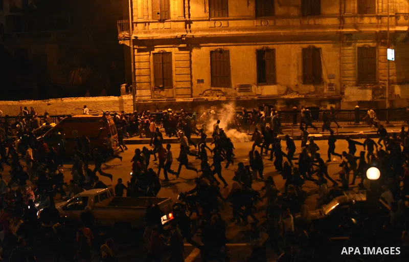 Egyptian anti-Mubarak protesters run for cover from tear gas during clashes with riot police at Abdel Moneim Riad, a main transportation hub for taxis and buses, after hearing the verdict of former Egyptian president Hos...