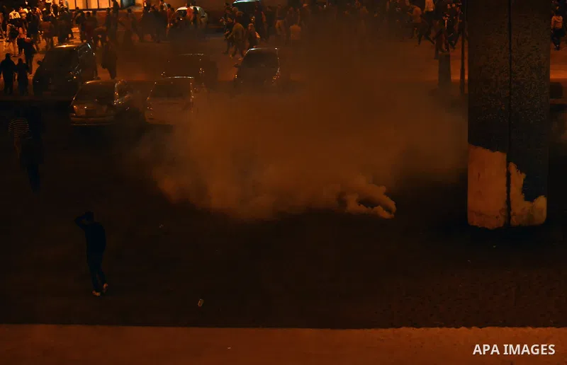 Egyptian anti-Mubarak protesters run for cover from tear gas during clashes with riot police at Abdel Moneim Riad, a main transportation hub for taxis and buses, after hearing the verdict of former Egyptian president Hos...