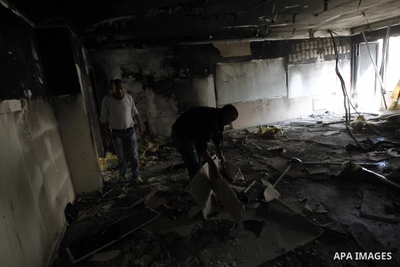 Workers inspect the damage on the aftermath of an arson attack that targeted first-grade classrooms at a Jewish-Arab school near the Arab neighborhood of Beit Safafa, in southern Jerusalem, on November 30, 2014. Scrawled...