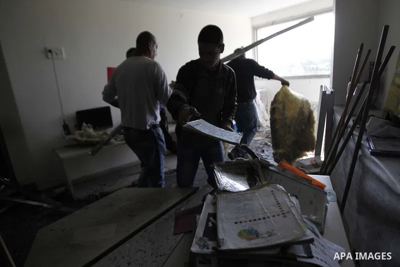 Workers inspect the damage on the aftermath of an arson attack that targeted first-grade classrooms at a Jewish-Arab school near the Arab neighborhood of Beit Safafa, in southern Jerusalem, on November 30, 2014. Scrawled...