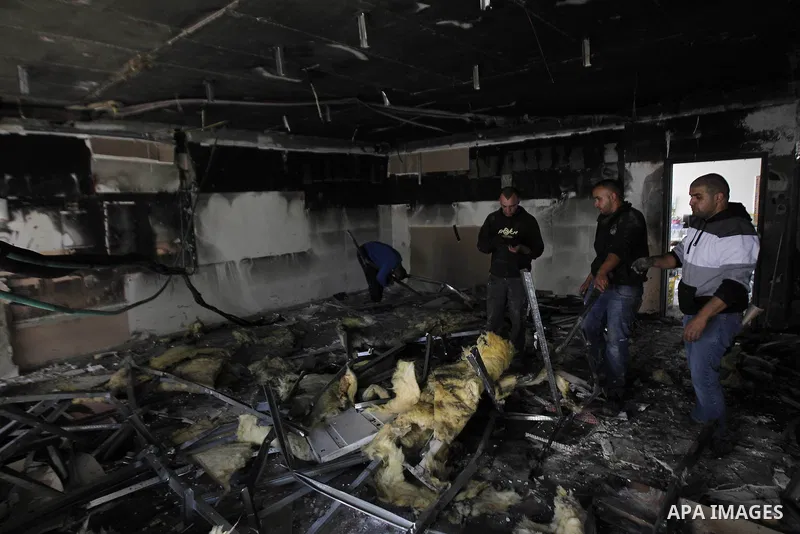 Workers inspect the damage on the aftermath of an arson attack that targeted first-grade classrooms at a Jewish-Arab school near the Arab neighborhood of Beit Safafa, in southern Jerusalem, on November 30, 2014. Scrawled...
