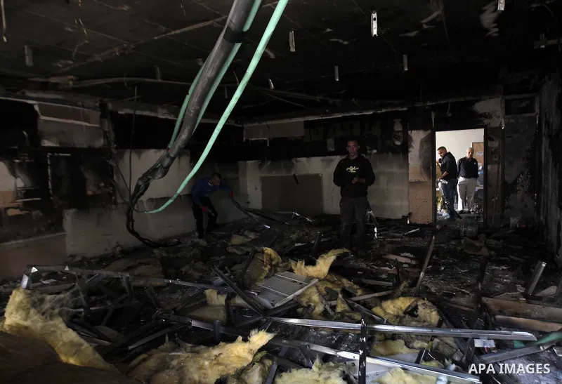 Workers inspect the damage on the aftermath of an arson attack that targeted first-grade classrooms at a Jewish-Arab school near the Arab neighborhood of Beit Safafa, in southern Jerusalem, on November 30, 2014. Scrawled...