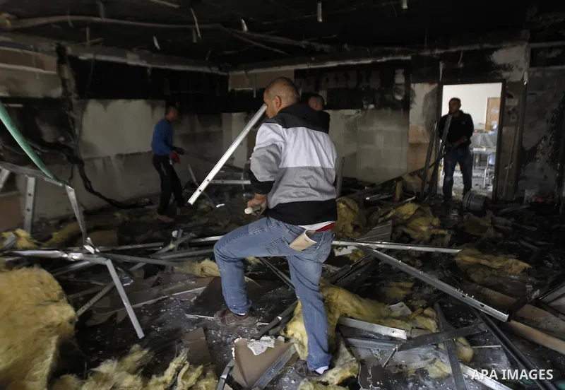Workers inspect the damage on the aftermath of an arson attack that targeted first-grade classrooms at a Jewish-Arab school near the Arab neighborhood of Beit Safafa, in southern Jerusalem, on November 30, 2014. Scrawled...