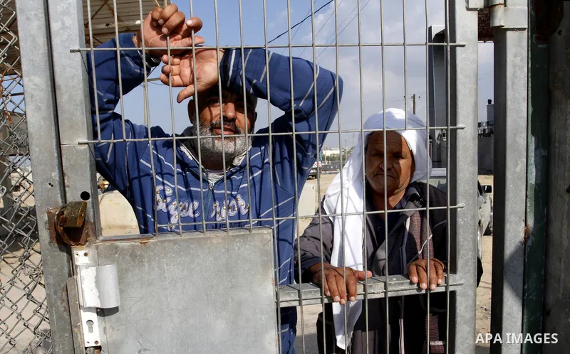 Palestinians look on as they wait their relatives to cross into Gaza through the Rafah border crossing between Egypt and southern Gaza Strip on November 30, 2014. Egyptian authorities reopened this week the Rafah crossin...
