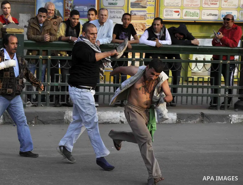 A Egyptian protester uses his shoe against a pro-regime supporter during a demonstration denouncing a recent court's decision to drop a murder charge against the former president, on December 5, 2014, on Abdel Moneim Ria...