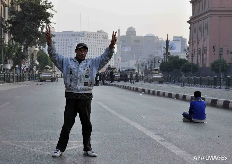 A pro-regime supporter holds Egyptian national flags in front of army vehicles positioned on Cairo's Tahrir square during a demonstration against a recent court's decision to drop a murder charge against the former presi...
