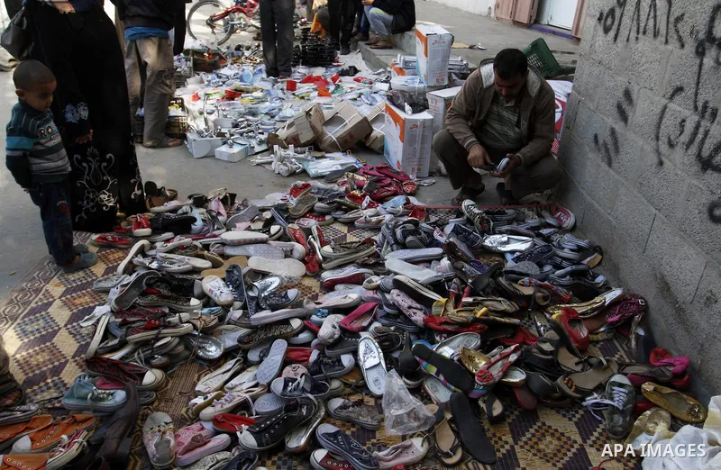 Palestinians looks at second hand shoes at a market in Rafah in the southern Gaza strip, December 06, 2014. Due to the current economic situation in Gaza Strip, many of the Palestinians resort to meet their needs of used...