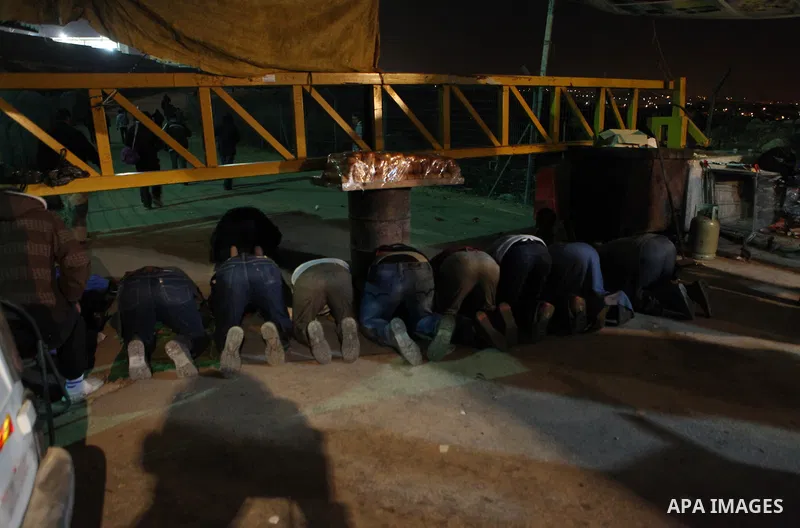 Palestinian labourers pray El-Fajr prayer as they wait in line to cross into jerusalem at Nilin crossing near the West Bank city of Ramallah December 8, 2014. Photo by Shadi Hatem