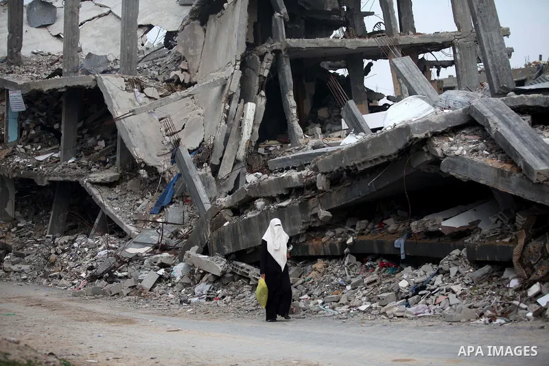 A Palestinian woman walks past the rubbles of houses, which were destroyed during the recent Israeli offensive on Gaza Strip, in Shijaiyah neighborhood, east Gaza City, December 8, 2014. According to housing minister Muf...